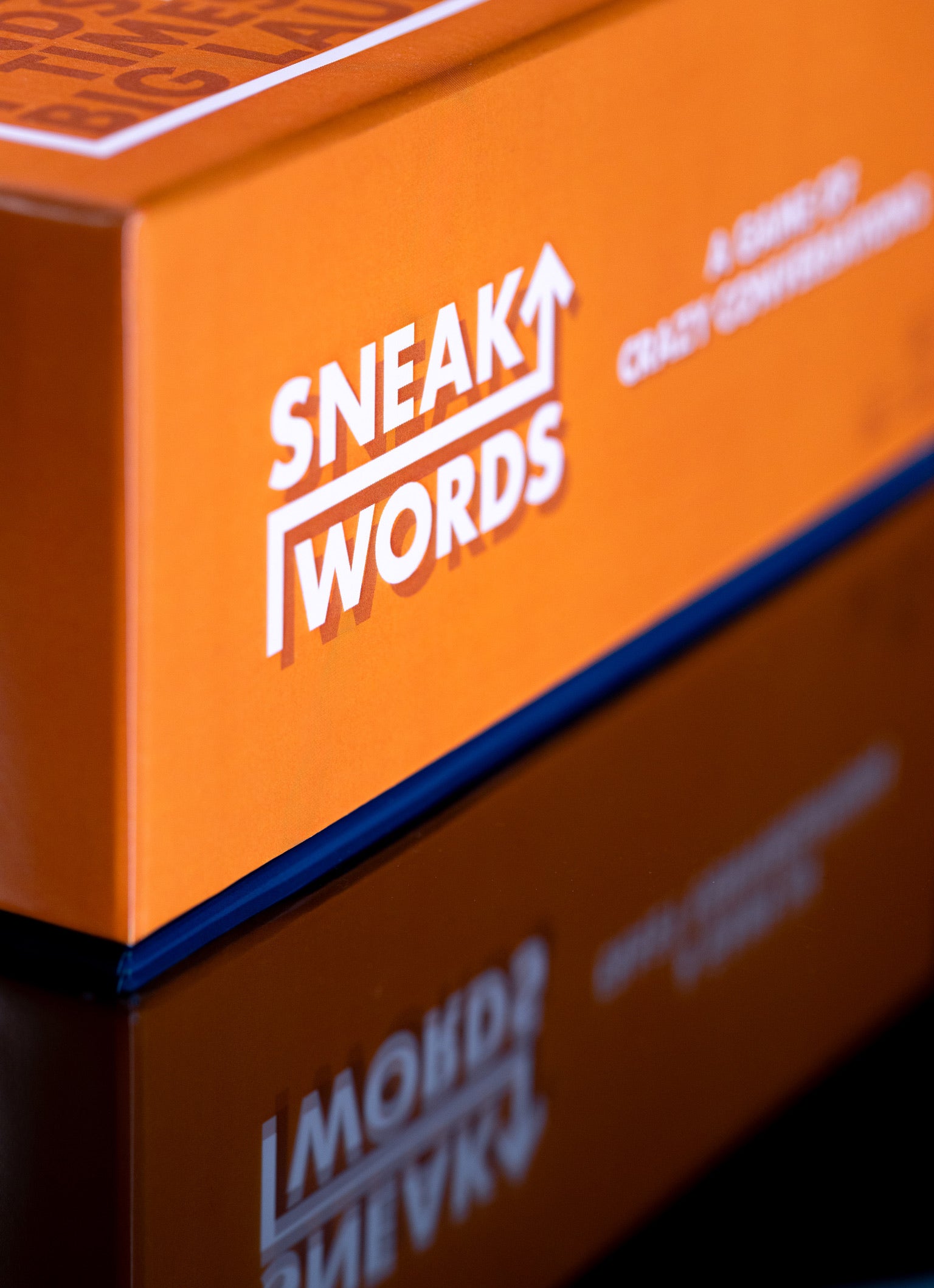 Orange box with 'SNEAK WORDS' branding on a reflective surface